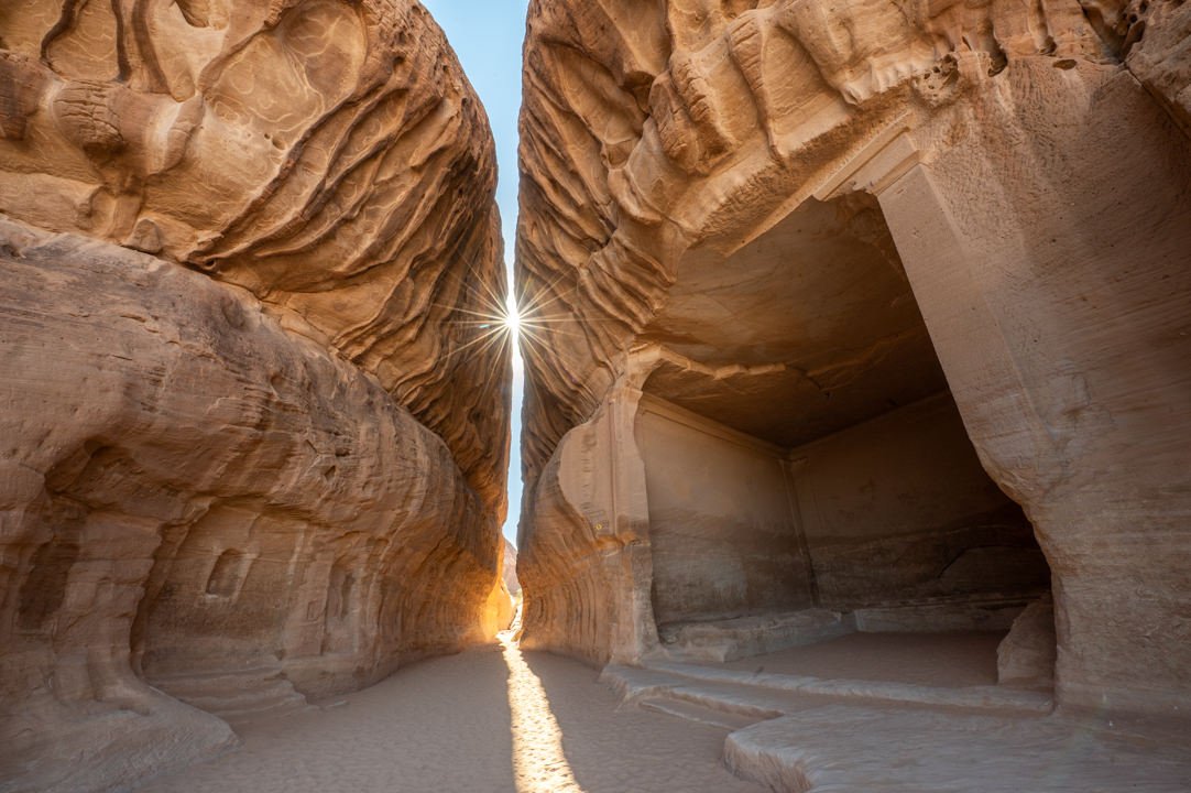 The image captures the grandeur of a rock-cut tomb in Madain Saleh, Saudi Arabia, showcasing the architectural prowess of the Nabataean civilization. The tomb, carved into the sandstone cliffs, stands as a testament to their advanced engineering skills and cultural heritage, inviting viewers to appreciate the historical significance and artistic beauty of this ancient site.