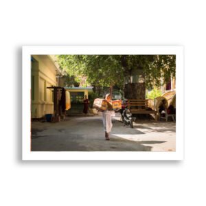 Young monk carries boxes in a sunny Bagan courtyard